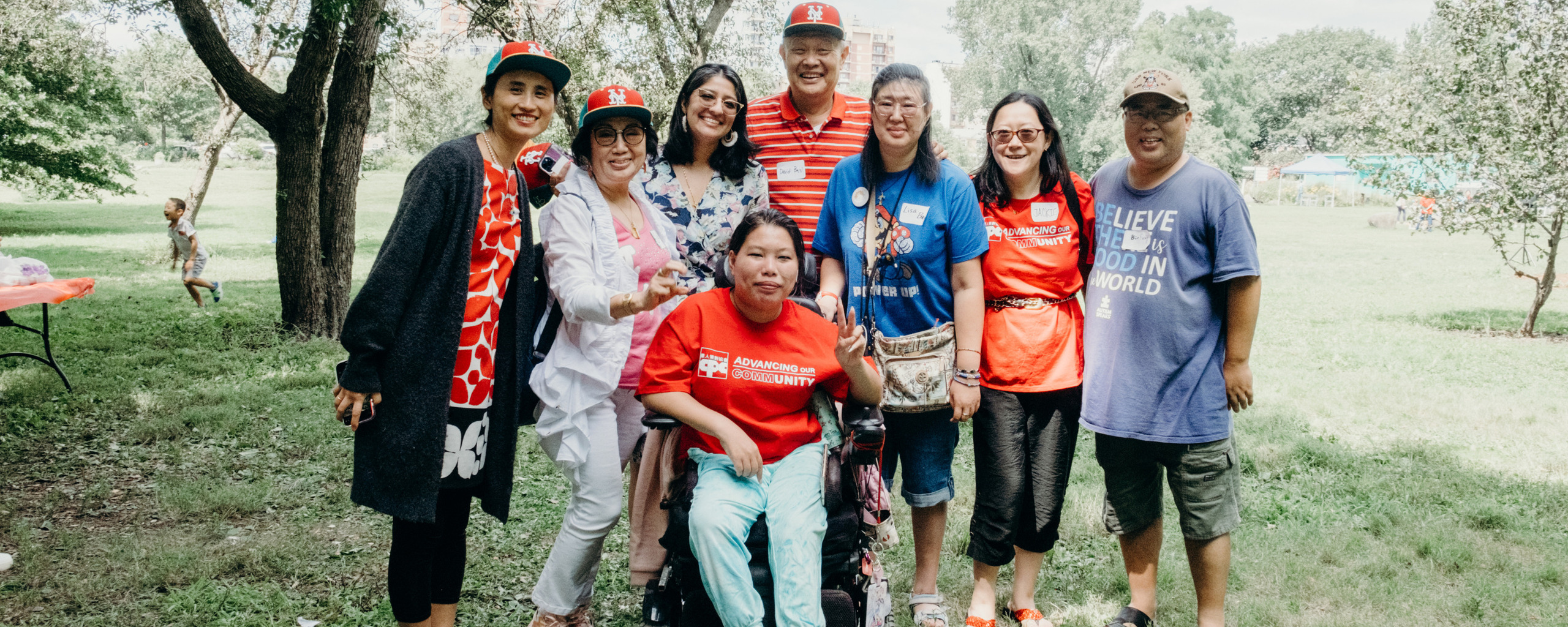 Group of adults smiling together outdoors at a community park event.