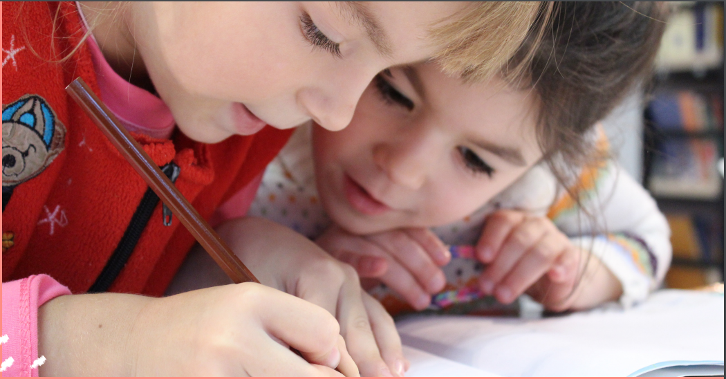 Two toddlers write sharing a pencil