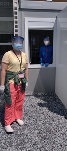 Two people wearing masks with one looking out a window