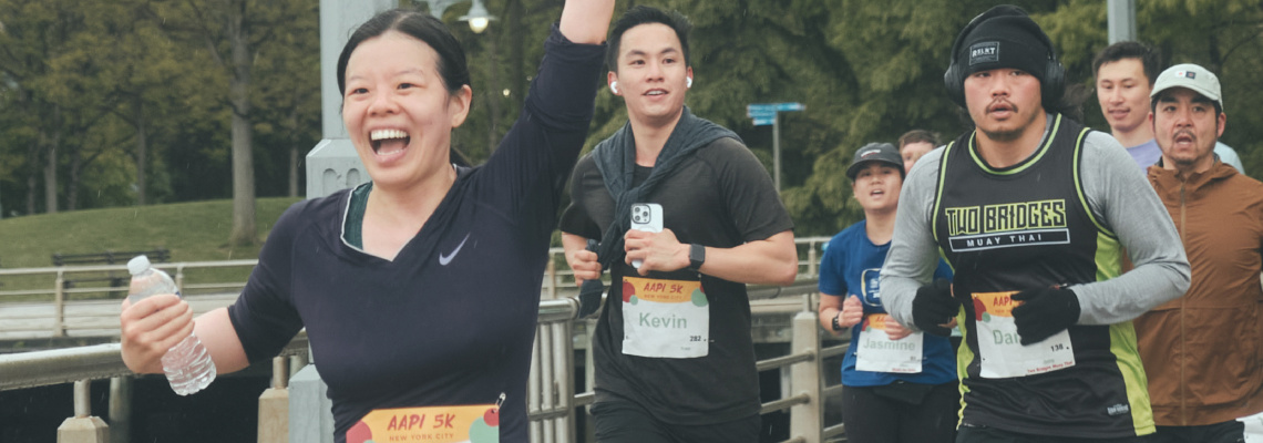 Group of enthusiastic runners smiling during an AAPI 5K race by the riverside.