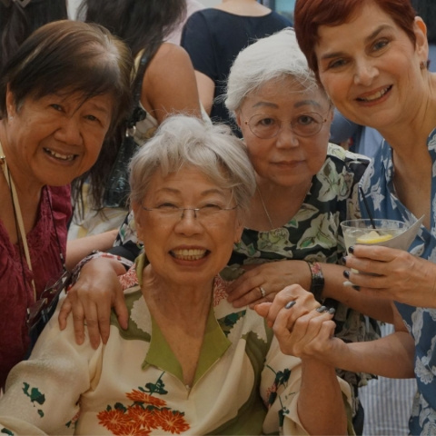 Four women smiling while being close to one another and posing for the photo