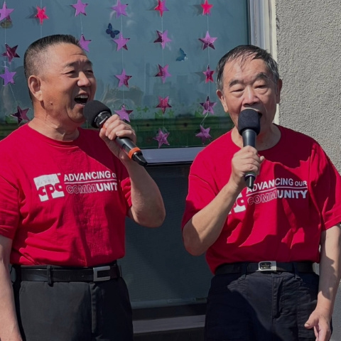 Two men wearing red CPC t-shirts speaking into microphones