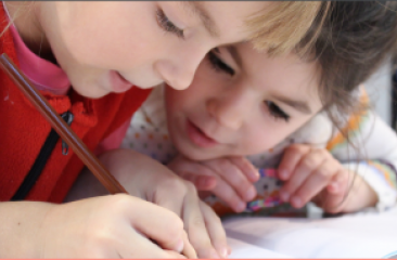 Two toddlers write sharing a pencil